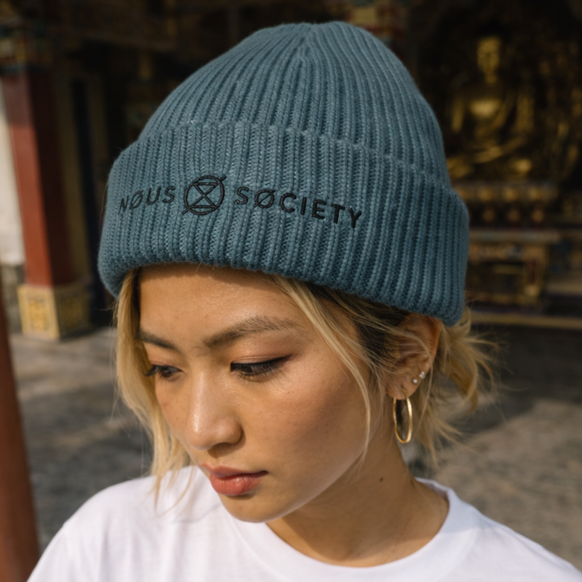 Person wearing a white t-shirt with Buddha graphic and a blue beanie in an outdoor setting.