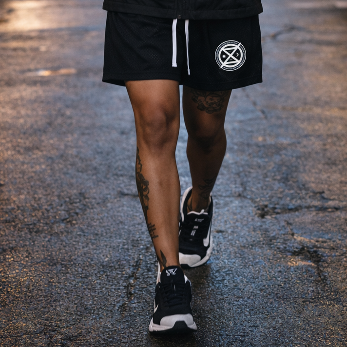 Person wearing a black hoodie and shorts with visible branding in an urban setting