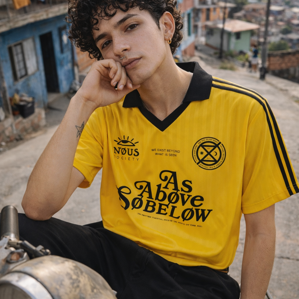 Person wearing a yellow 'As Above, So Below' shirt sitting on a motorcycle in an urban setting.