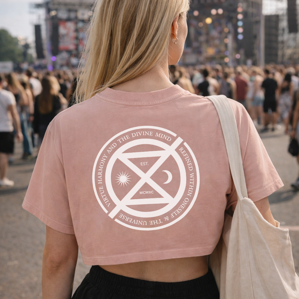 Person wearing a pink t-shirt with a white graphic design at a music festival.