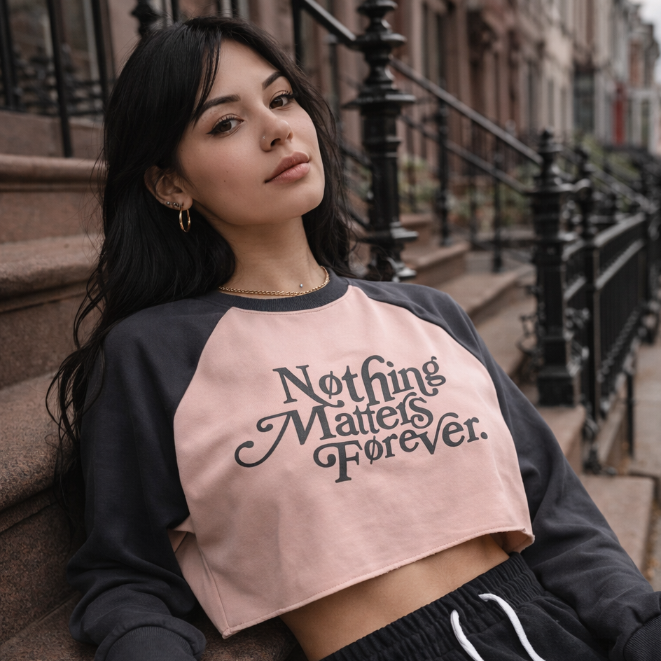 Woman wearing a black and pink crop top with 'Nothing Matters Forever' text, sitting on steps.